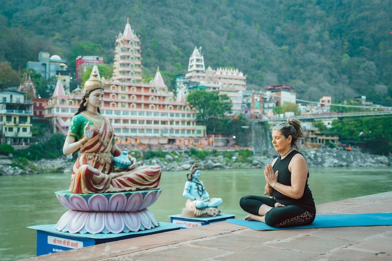 <img src="topinfo_bg.png" role=“ A Woman Meditating in Front Ganges - Pages ”>